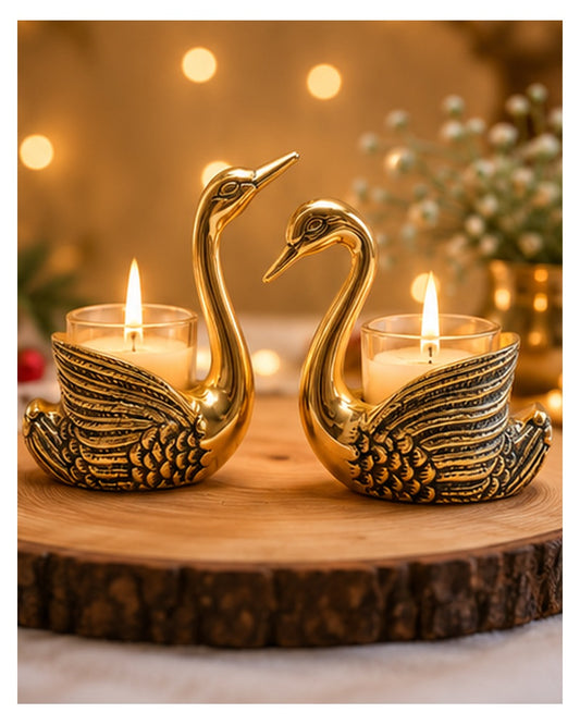 Golden swan tealight holders lit on a wooden table