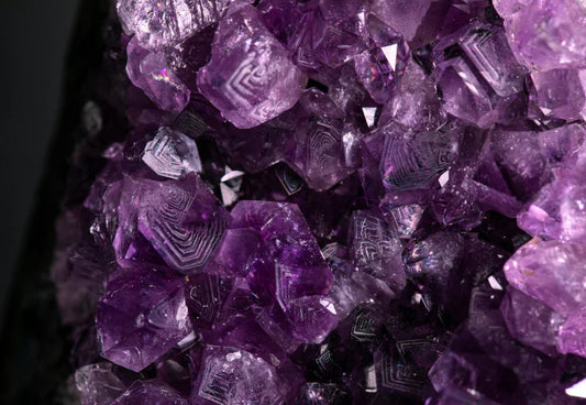 Close-up of vibrant purple amethyst crystal cluster with geometric formations on a dark background
