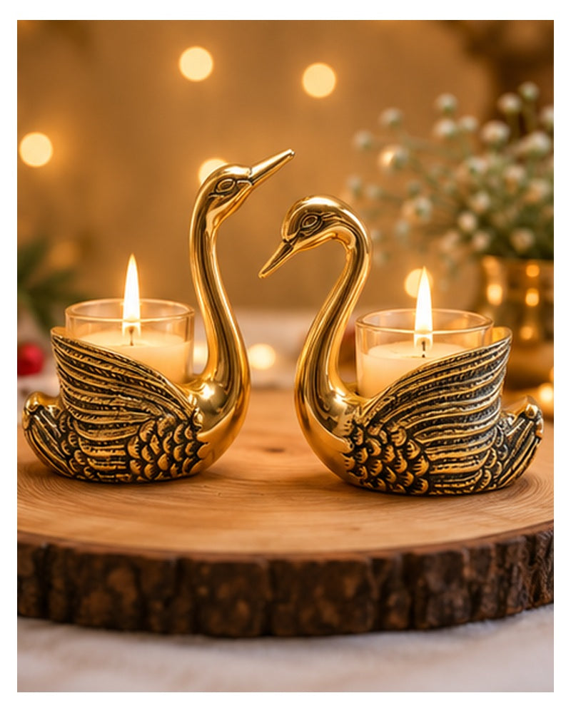 Golden swan tealight holders lit on a wooden table