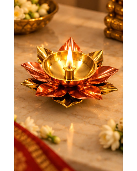 Copper and brass lotus diya, lit, in a festive setting
